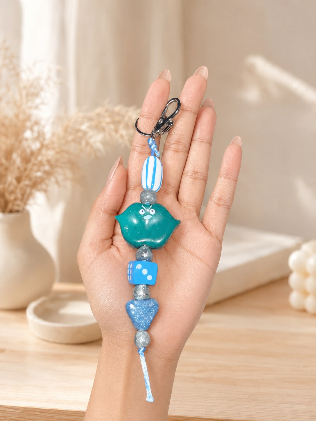 A blue and teal beaded keychain charm with a metal clasp.

Blue Mood Buddy handmade blue polymer clay character keychain