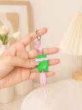 A small keychain charm shaped like a green character wearing a pink dress, with a metal key ring and tassel.

Pink Pop Pixie handmade pink polymer clay character keychain