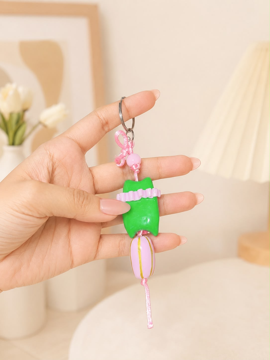 A small keychain charm shaped like a green character wearing a pink dress, with a metal key ring and tassel.

Pink Pop Pixie handmade pink polymer clay character keychain